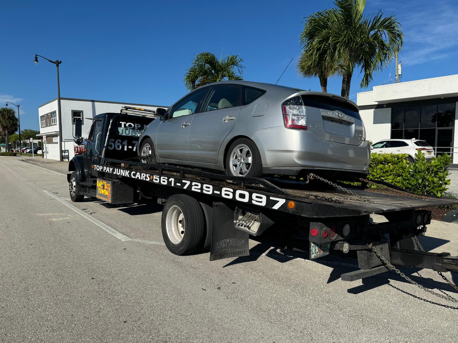Amy’s Towing flatbed carrying a silver Toyota Prius, with Top Pay Junk Cars lettering